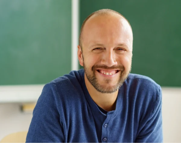 Lächelnder Mann vor einer Schultafel